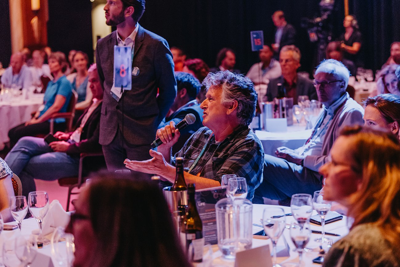 Sitting man speaking in microphone during dinner